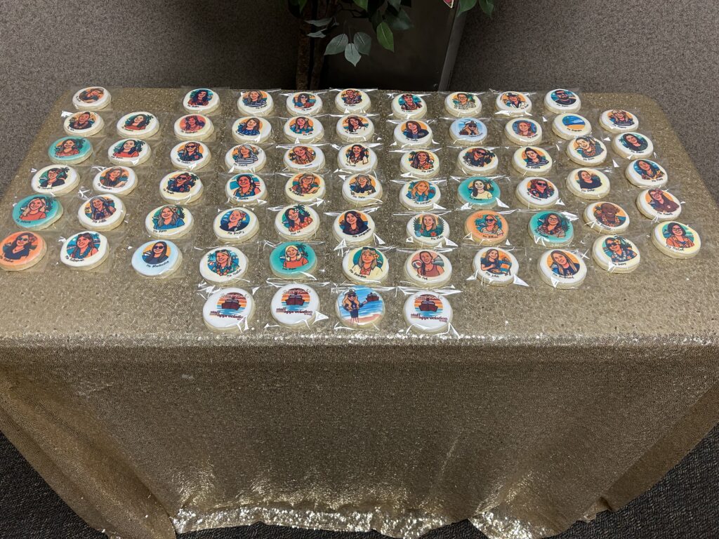 A table covered in a gold tablecloth displays numerous decorated cookies featuring diverse illustrations of people.